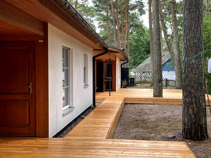 Umlaufende Holzterrasse, die um gewachsene Kiefern herum gebaut wurde