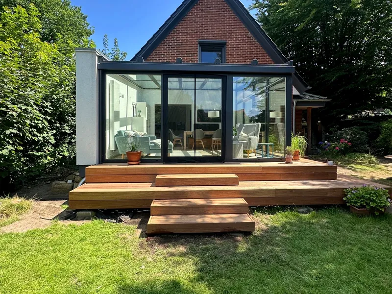 Holzterrasse mit Stufenanlage vor einem Wintergarten-Anbau
