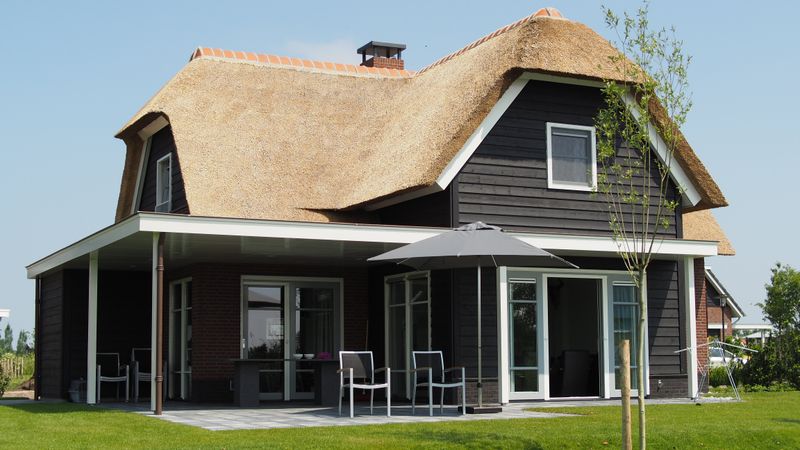 Landhaus mit überdachter Terrasse, Sonnenschirm und Gartenmöbeln