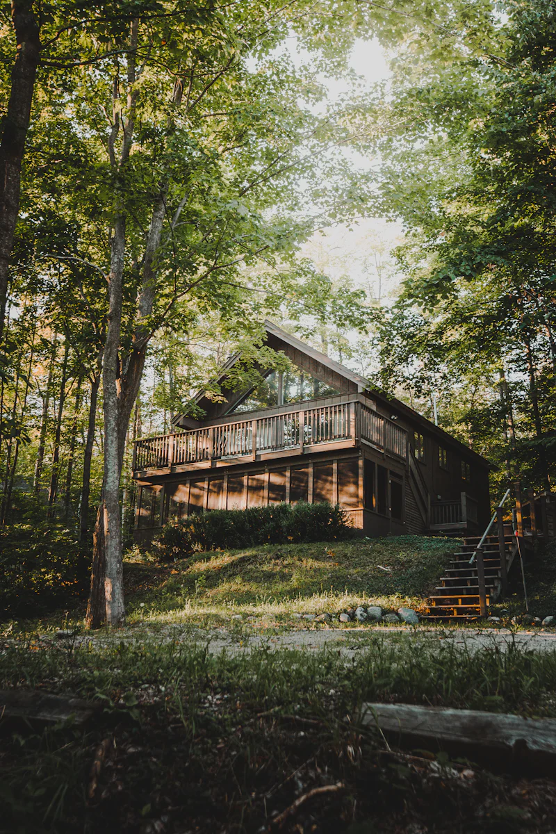 Holzhaus mit umlaufendem Deck und Geländer zwischen hohen Bäumen